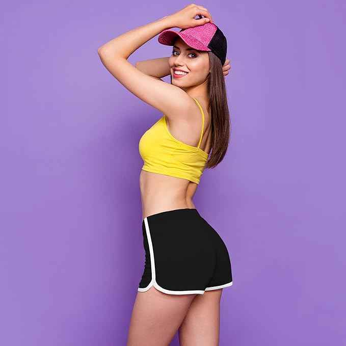 Woman in yellow sports bra and black shorts with a pink and black cap on a purple background by brachy